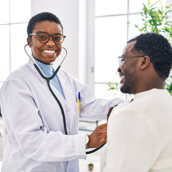 Man and woman doctor and patient having medical consultation auscultating chest at clinic