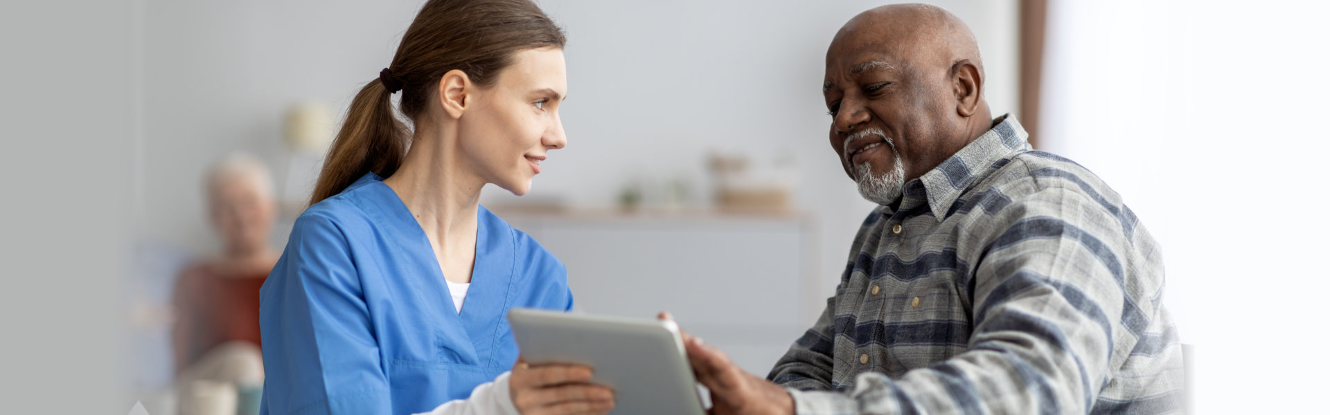 caregiver and a man using tablet