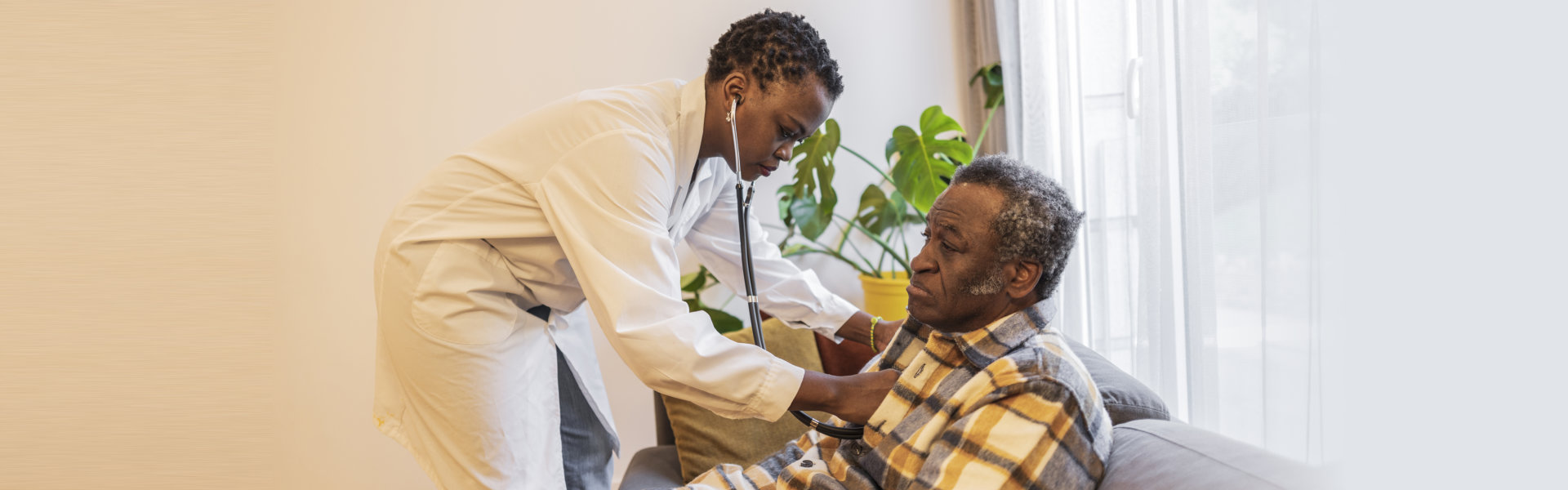 A young female doctor examines an elderly man at home